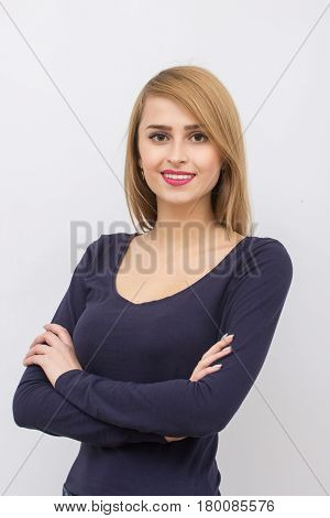 Girl posing with her hands crossed on a light gray background in the studio