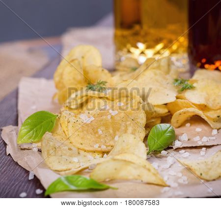 Potato chips with salt and greens on a table in a pub on a background of beer. Chips with greens as a snack to beer. October Beer Fest.