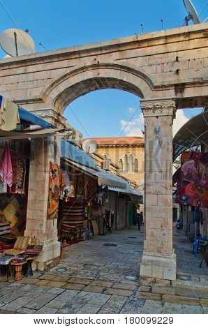 JERUSALEM, ISRAEL - DECEMBER 26, 2016: medieval gate leads to the Aftimos Bazaar with its noisy merchants and colorful goods in the Christian quarter of the old city of Jerusalem