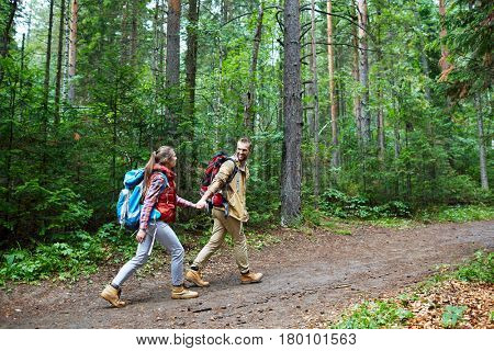 Couple of tourists walking along forest path on sumemr day