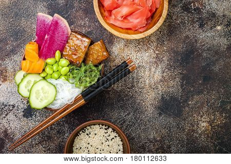 Vegan tofu poke bowls with seaweed watermelon radish cucumber edamame beans and rice noodles. Copy space background overhead flat lay