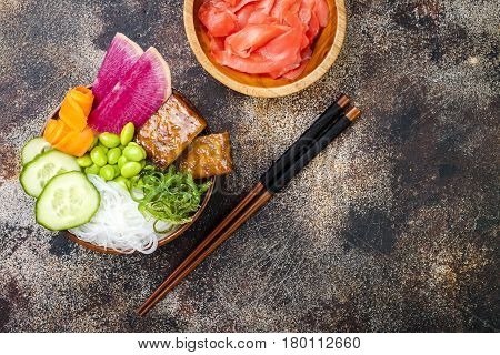 Vegan tofu poke bowls with seaweed watermelon radish cucumber edamame beans and rice noodles. Copy space background overhead flat lay
