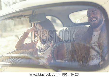 Beautiful young couple sitting in a car guy is driving while the girl is smiling and having fun on the road. Focus on the boyfriend