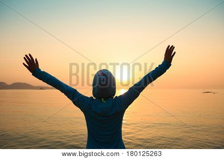 Happy woman with open arms at sunset on beach