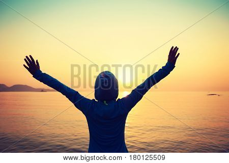 Happy woman with open arms at sunset on beach