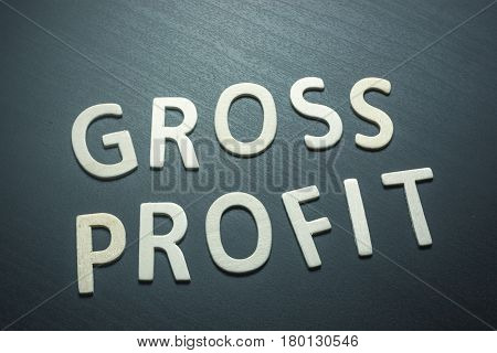 Gross profit written with wooden letters on a green background to understand a concept of economics and finance