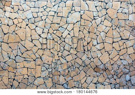 Close up wall covered with pieces of light brown stone forming mosaic pattern abstract texture background