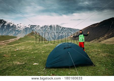 Kazbegi, Georgia - May 22, 2016: Young Tourist Man Is Putting Up A Tent Near Gergeti Trinity Church Or Tsminda Sameba - Holy Trinity Church. Church Is Situated At An Elevation Of 2170 Meters