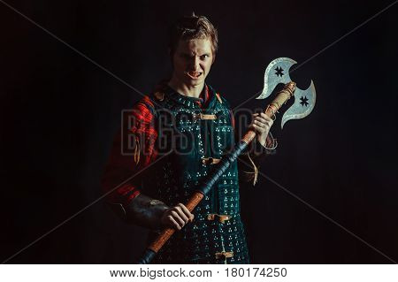 Young Medieval Warrior With The Axe. Dark Background.