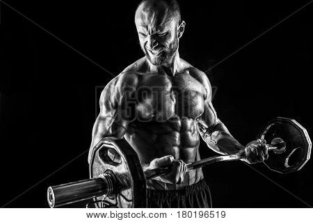 Studio portrait of topless bodybuilder performing biceps exercise with concentrated face over black background   