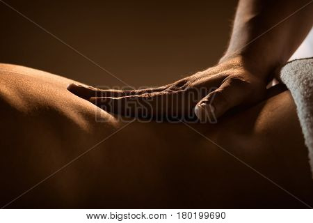 Massage closeup view with hands of professional masseur. Charming lighting