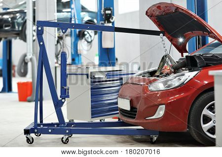 automobile mechanic a crane removed the engine from the car. repairing auto in automobile store.