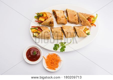 Indian popular snack food called Vegetable spring rolls or veg roll or veg franky made using paneer or cottage cheese and vegetables wrapped inside paratha/chapati/roti with tomato ketchup.