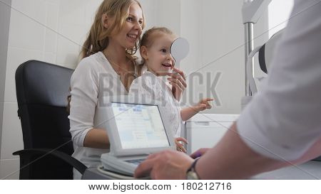 Medicine for children - optometrist in clinic checking little girl's vision, close up