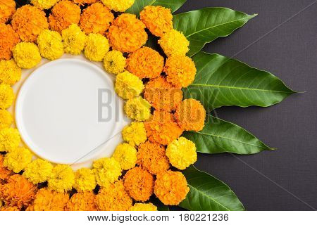 flower rangoli made using marigold or zendu flowers and mango leaves over black background with copy space in the middle, selective focus