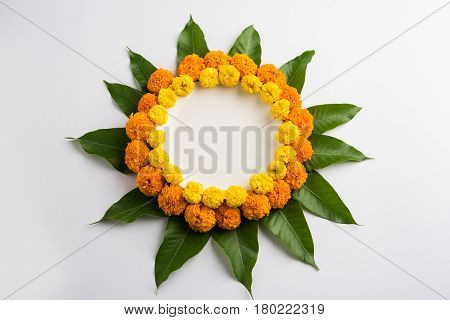 flower rangoli made using marigold or zendu flowers and mango leaves over black background with copy space in the middle, selective focus