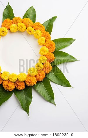 flower rangoli made using marigold or zendu flowers and mango leaves over black background with copy space in the middle, selective focus