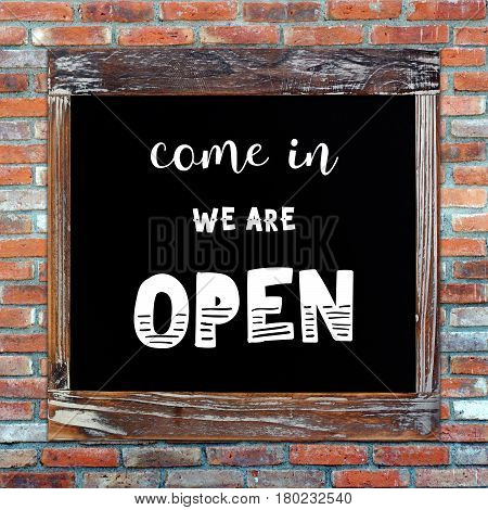 Open sign on vintage chalk board over brick wall background
