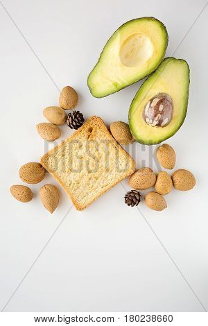 Sliced avocado oats toast and whole almonds view from above white background breakfast