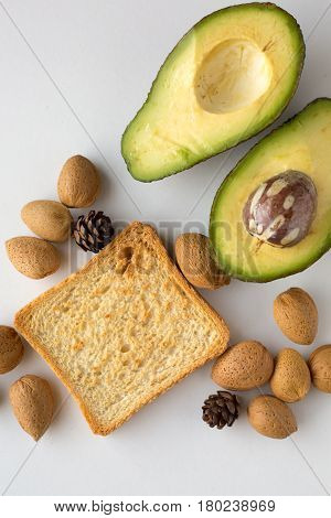 Sliced avocado oats toast and whole almonds view from above white background breakfast