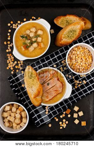 Pea soup with carrot and bacon in bawl on wooden table