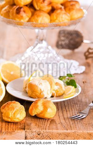 Profiteroles with lemon cream on white dish.