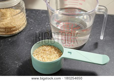 Measure scoop with brown rice on kitchen table