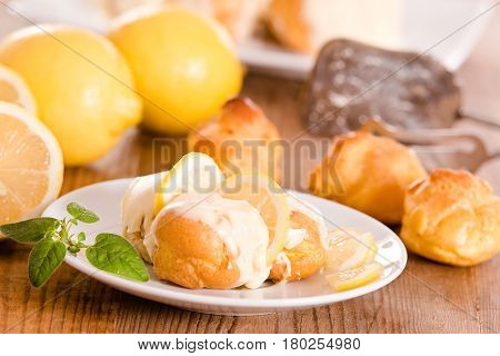 Profiteroles with lemon cream on white dish.