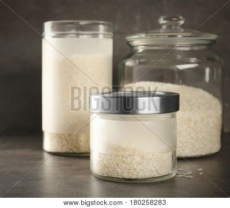Glass jars with rice on grey table