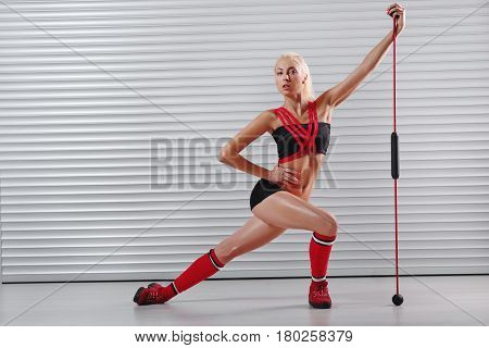 Horizontal full length shot of a beautiful blonde haired female fitness model exercising with training stick showing off her strong body and perfect abs copyspace sports dieting femininity athlete.