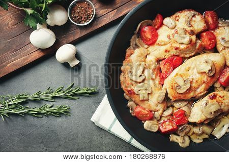 Frying pan with delicious chicken marsala on table