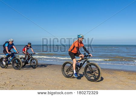Kijkduin the Netherlands - April 2 2017: group of men riding bikes on sunny beach