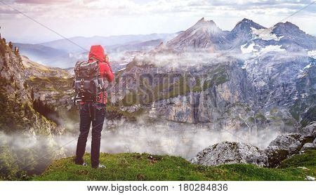 Tourist with backpack and camera enjoyingview on top of a mountain clouds photography sky
