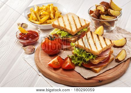 Club Sandwich With Tomato, Lettuce, Bacon, Ham And French Fries