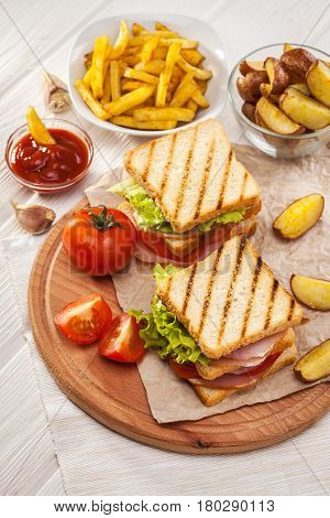 Club Sandwich With Tomato, Lettuce, Bacon, Ham And French Fries