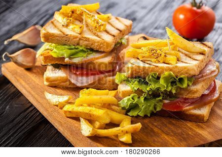 Club Sandwich With Tomato, Lettuce, Bacon, Ham And French Fries