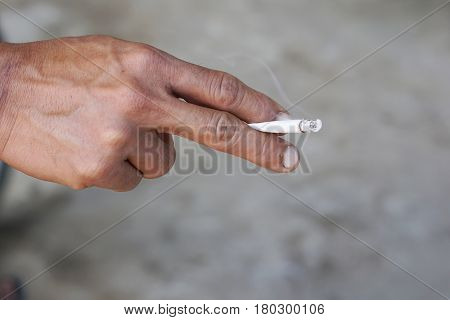 Asian man hand holding cigarette between his two fingers