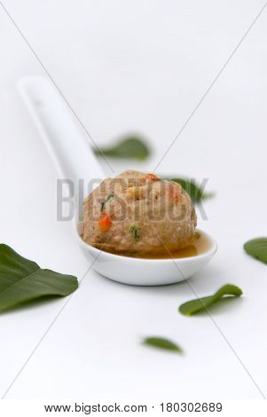 Pork meatball with chili, in a kafir lime leaf broth, served on a small white spoon