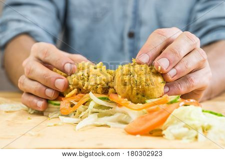 Making vegan flat bread sandwich with falafel. Male hands laying falafel balls fresh vegetables on lavash flat bread for making vegan kebab sandwich
