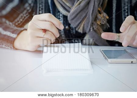 a man with a pencil in one hand is calculating his monthly expenses on smartphone