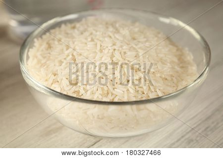 Glass bowl with rice on wooden table