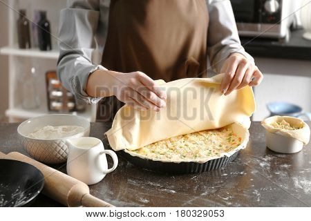 Woman making delicious chicken pot pie on kitchen table