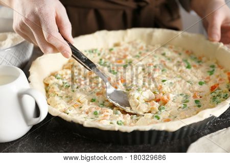 Woman making delicious chicken pot pie on kitchen table