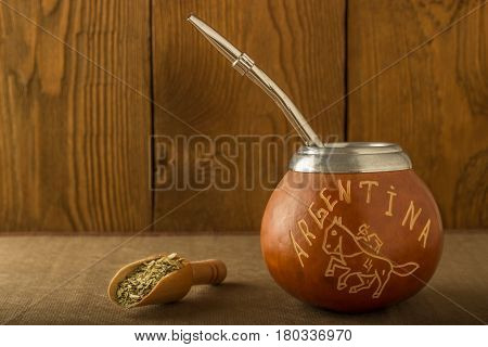 Calabash with yerba mate and a wooden spoon against the background of a tree