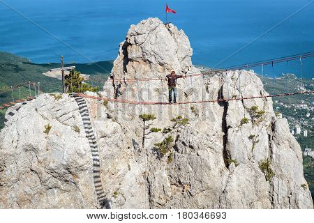 CRIMEA, RUSSIA - MAY 19, 2016: Tourist walking on a rope bridge on the Mount Ai-Petri. Ai-Petri is one of the highest mountains in the Crimea and tourist attraction.