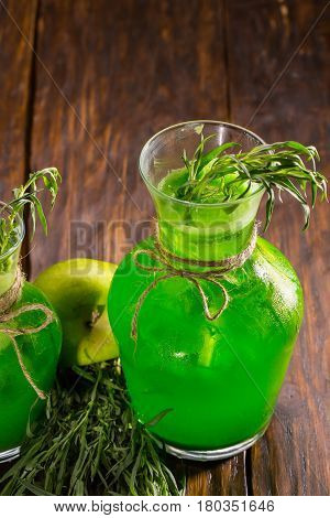 An estragon soft drink with a grass an estragon, ice and apple