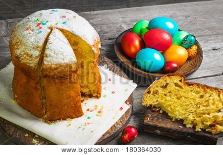 Easter sweet bread Orthodox kulich paska willow twigs. Easter Colorful eggs on gray wooden background. Holidays breakfast. Palm Sunday. Space for text.