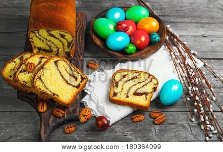Easter card. Easter treat cozonac painted chicken and quail eggs. Easter willow pecans nuts. Rustic style gray wood background.