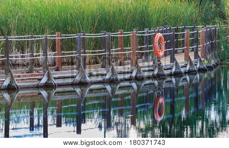 Serene floating boardwalk with orange life preserver reflected in water