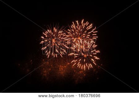 Three colorful bursts of red/white fireworks fill the center of the frame at the International Fireworks Festival at the Old Port of Montreal, Quebec at night in July